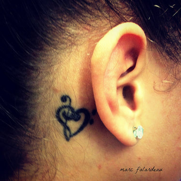 female ear and heart tattoo next to it