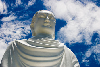 large Buddha statue, blue sky and white clouds in background