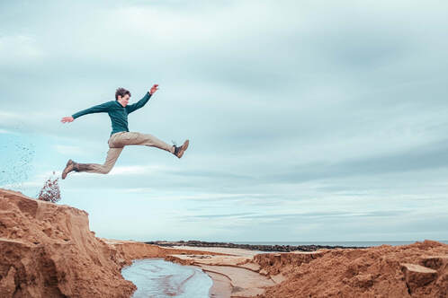 man leaping over cliff