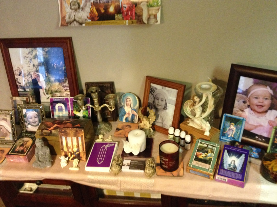 sacred space table with oracle cards, candles, statues, picture frames