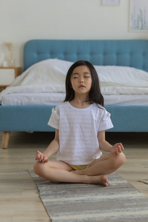 female child meditating at home