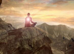 person meditating on cliff with bright light coming out of them