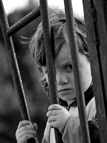 sad child behind bars
