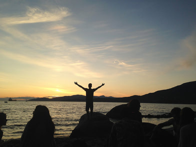 silhouette of person at beach at sunset with arms raised up