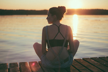 spiritual woman sitting on dock in sunset