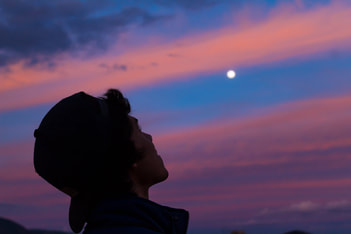 man looking up at moon purple sky