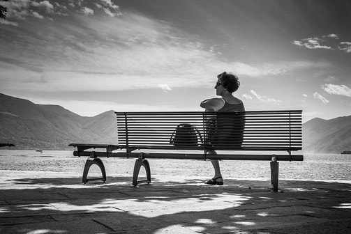 woman sitting reflecting on outdoor bench