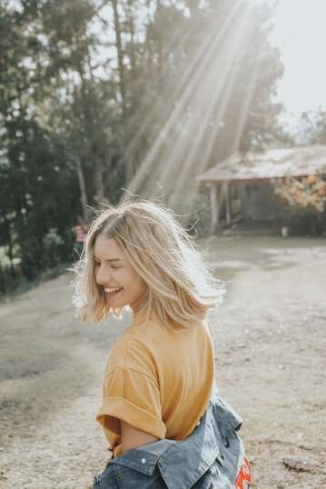 spiritual woman smiling as sunlight rays shine on her outside