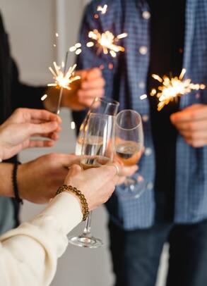 hands holding champagne glasses and sparklers celebrating new years eve