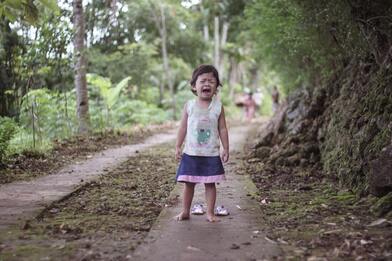 little girl in bare feet crying alone in forest