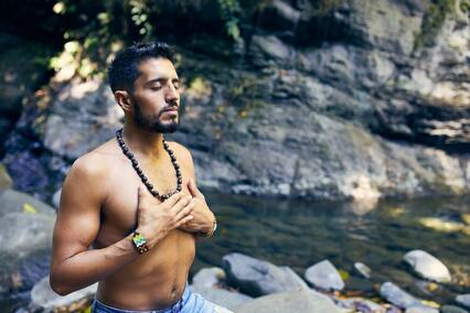 spiritual man meditating by rocks and water