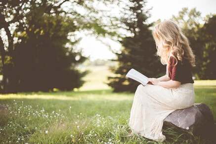 woman sitting on grass with book journal