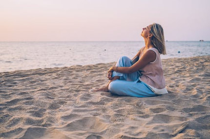spiritual woman sitting on beach feeling energetically and spiritually expansive