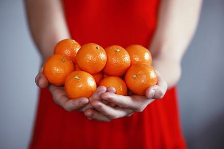 woman in red dress holding bright oranges