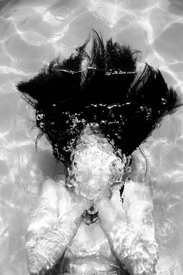 emotional woman under water covering face
