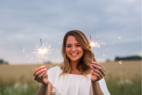 happy woman holding sparklers in nature