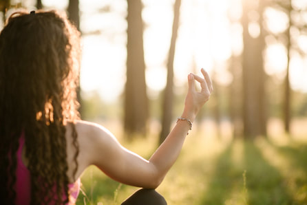 woman meditating in forest light