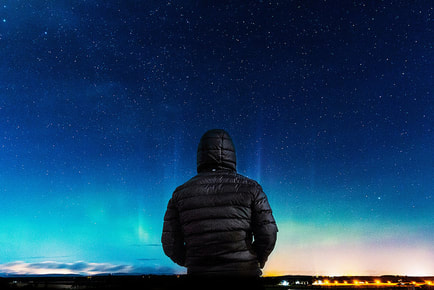 man in black hoodie alone looking at cosmos