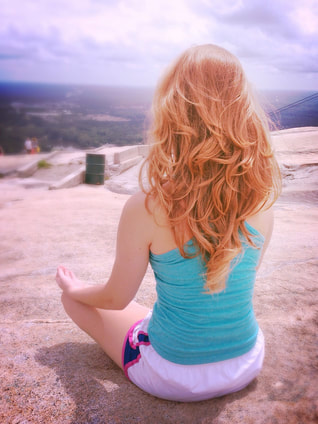 woman meditating on rock looking at view