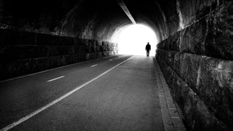 man walking through tunnel with light