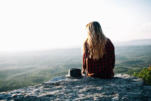 spiritual woman sitting on rock in nature reflecting