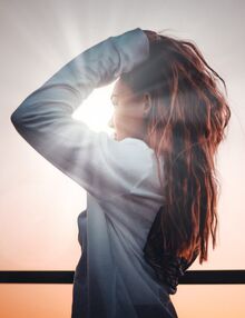 Woman looking at sunrise light shining on face