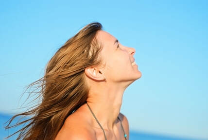 happy woman looking up, blue sky in a state of higher consciousness