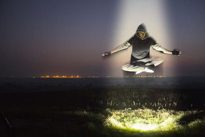 man levitating in light over grass