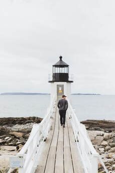 man alone walking towards lighthouse
