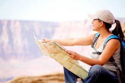 woman looking at map sitting on mountain