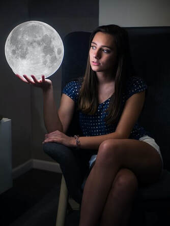 woman on coach reflecting, holding moon in hand 