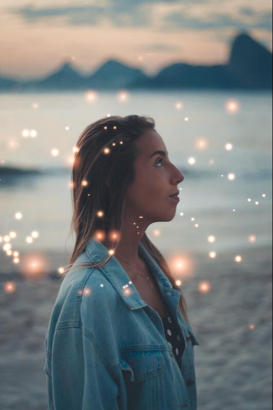Woman feeling spiritual connection with glowing lights on beach