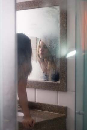 woman looking at reflection in foggy mirror