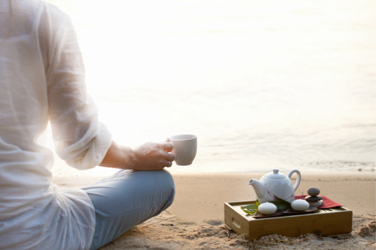 woman sitting on beach in sacred space with tea