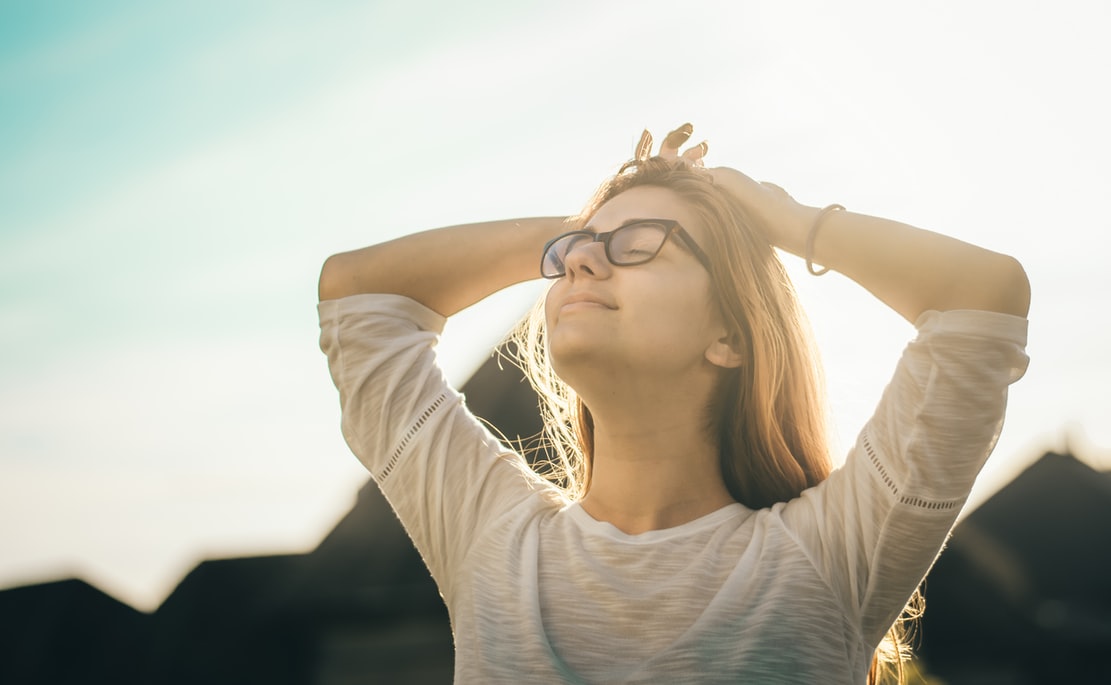 woman breathing in fresh air with sunlight on head
